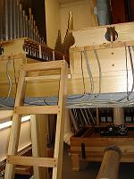  A view of the other side chamber, showing air pipes, reservoir, and ladder to a walkboard between two windchests. Some of the larger pipes have been installed, but most holes remain empty. Note the control cables entering the wind chests.